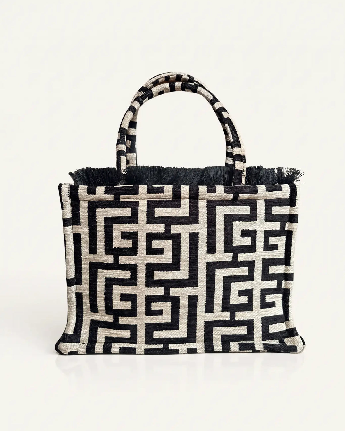 Rückansicht der Domna Medium Tote Bag von Sorena Greece, Mäandermuster in Schwarz und Elfenbein mit schwarzem Fransensaum, erhältlich bei SIMORA in der Schweiz.
