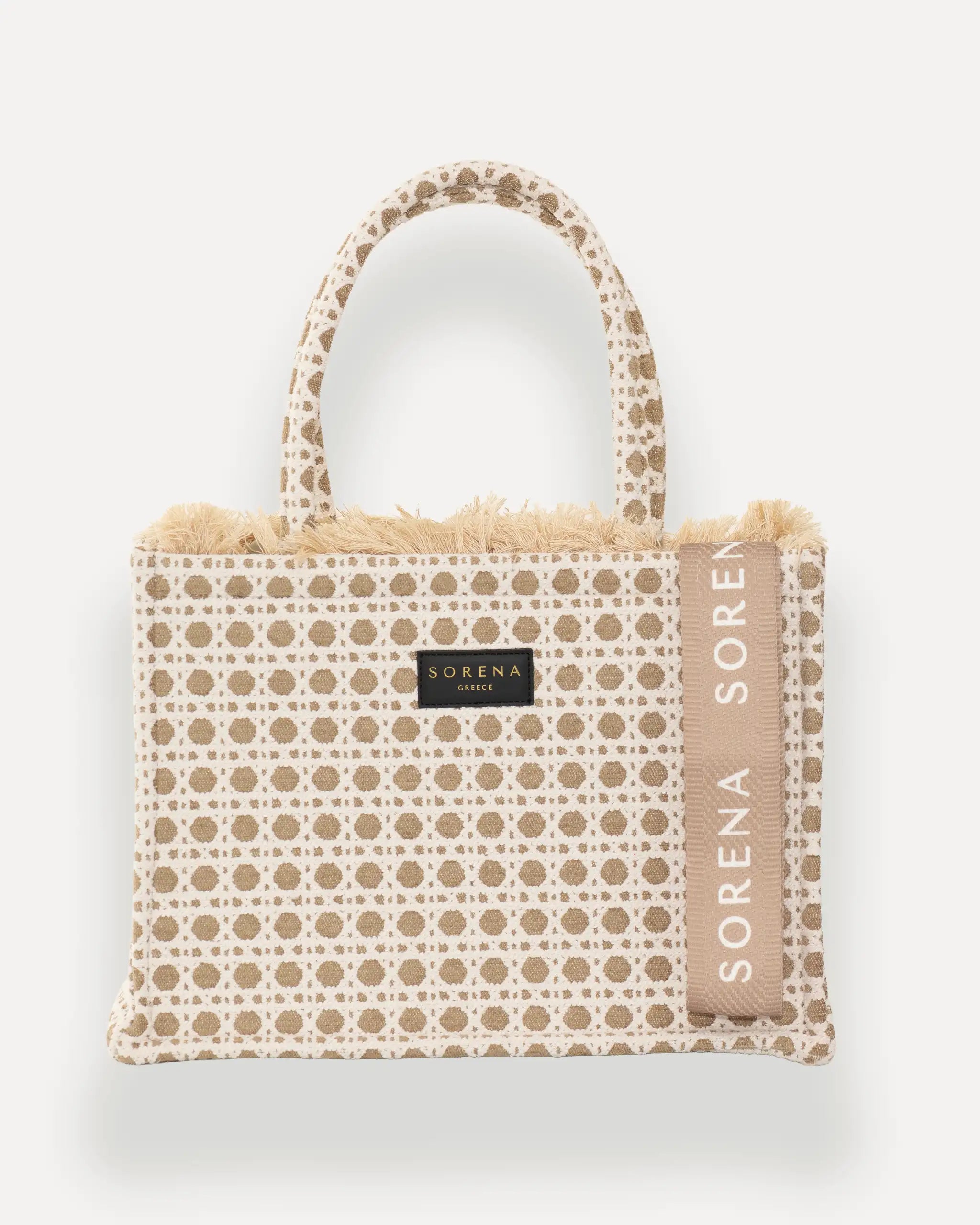 Frontansicht der Sorena Greece Medium Tote Bag – beiges Polka-Dot-Muster, Fransen, Label und vertikales Branding sichtbar, hochwertige shopper tasche damen schweiz mit Designfokus.