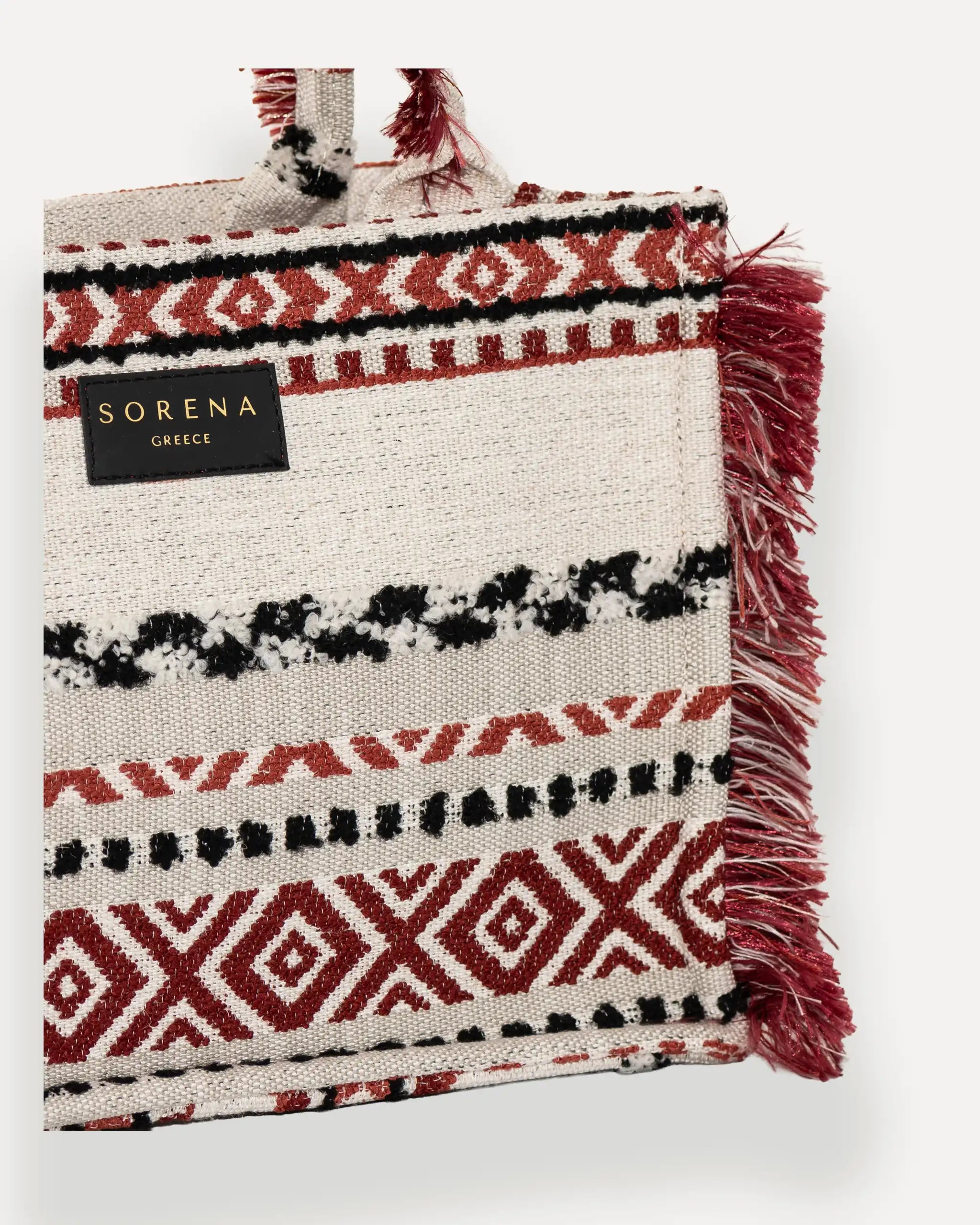 Detailansicht der Sorena Greece Large Tote Bag – strukturierte Oberfläche mit Webtextur in Rot, Schwarz und Beige, Label „SORENA GREECE“, goldfarbene Karabiner, perfekte tote bag für Business & Freizeit, tasche mit swiss trust und garantie.