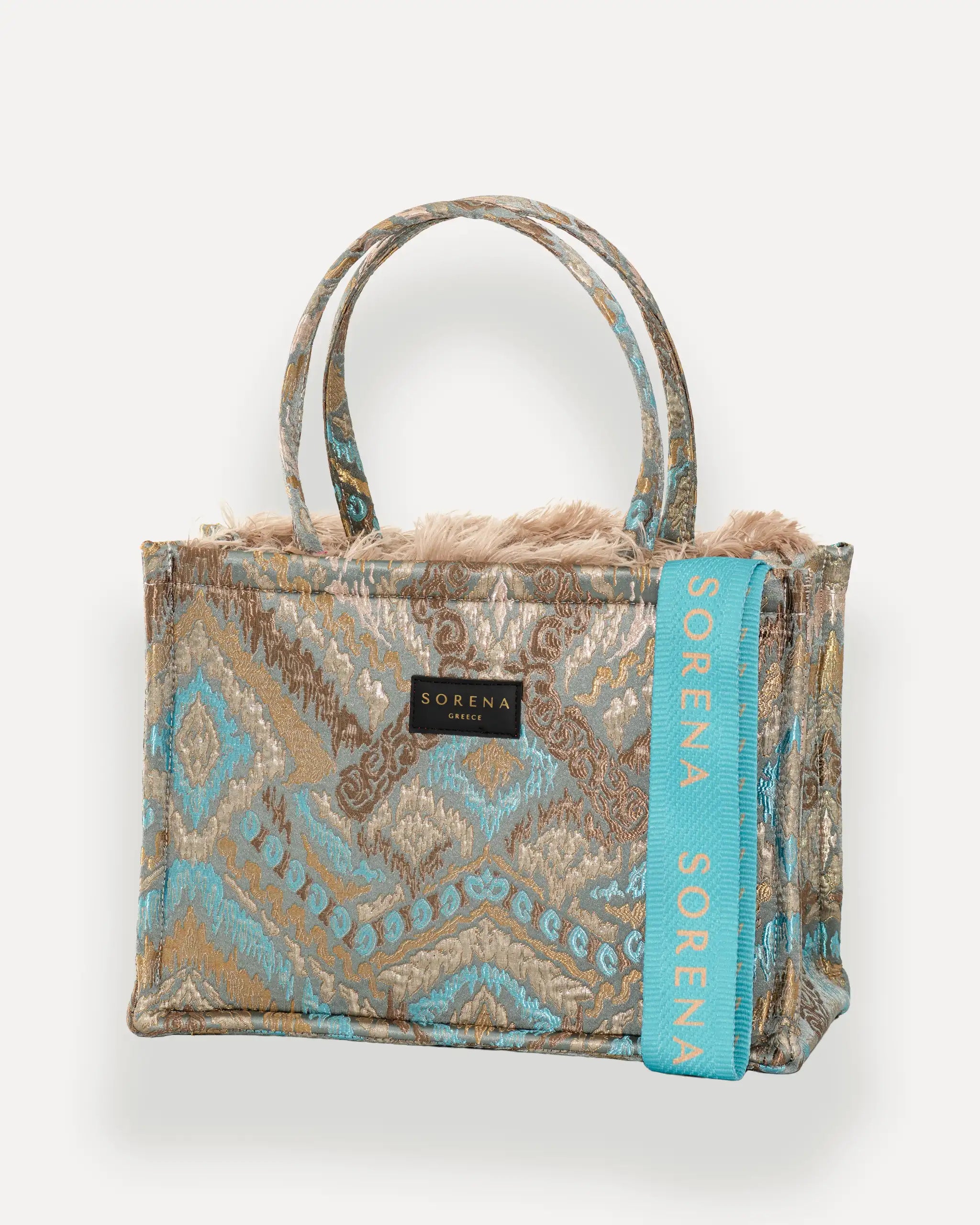 Sorena Greece Medium Tote Bag linksseitig getragen – shopper beige mit federartigem Muster, Fransen und rosa „SORENA“-Band, ideale tasche für dinner und city looks, bags schweiz mit Designfokus.