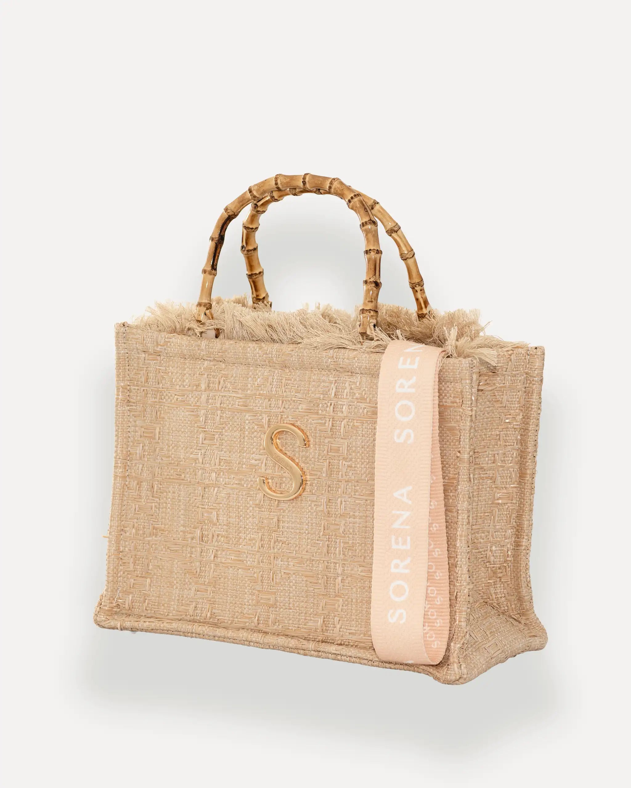 Sorena Greece Medium Tote Bag linksseitig getragen – strukturierte shopper beige mit Fransen und rosa „SORENA“-Band, ideale tasche für dinner und city looks, bags schweiz mit Designfokus.
