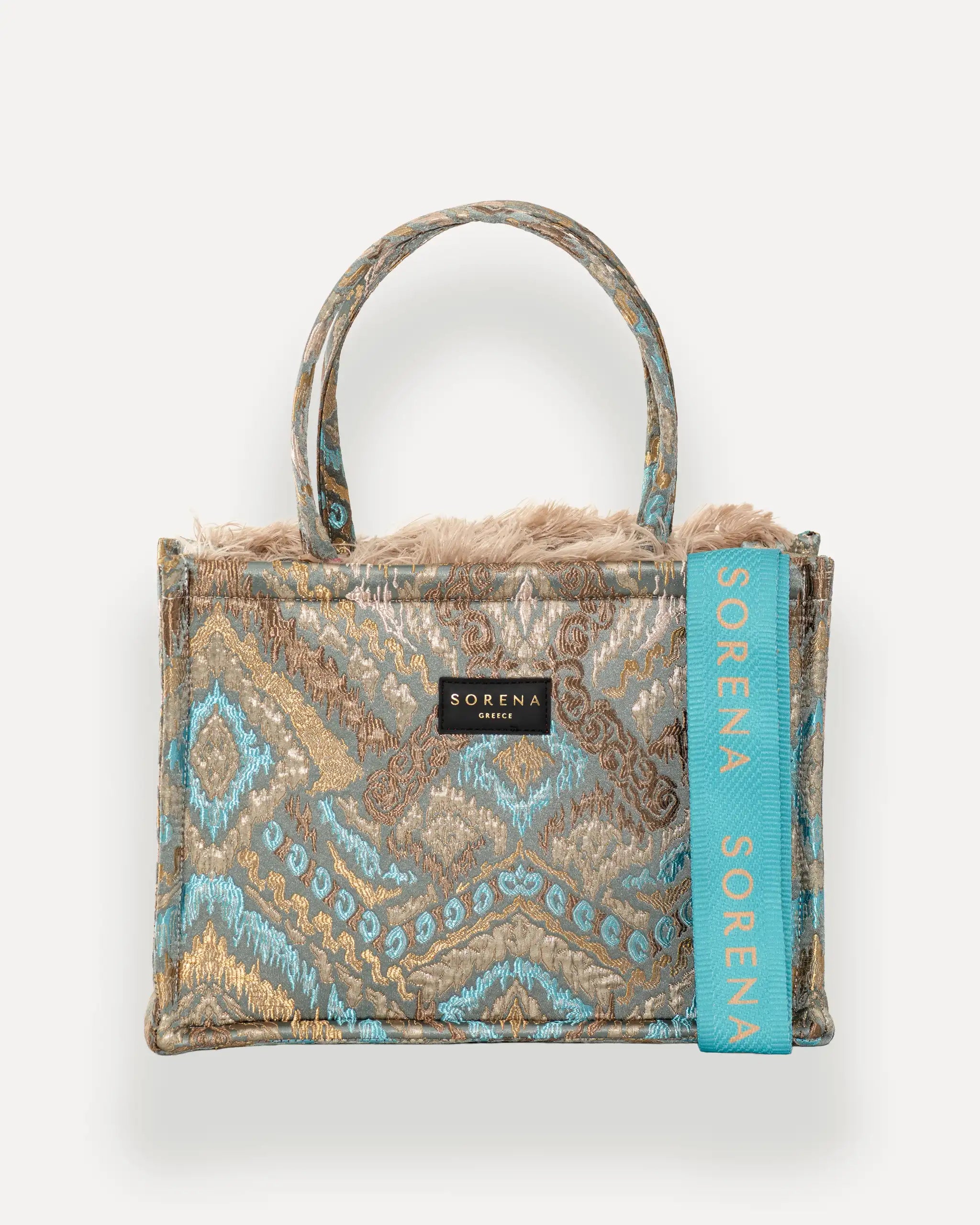 Frontansicht der Sorena Greece Medium Tote Bag – federartige Chevron-Struktur in warmen Tönen, Fransen, Label und vertikales Branding sichtbar, hochwertige shopper tasche damen schweiz mit Designfokus.
