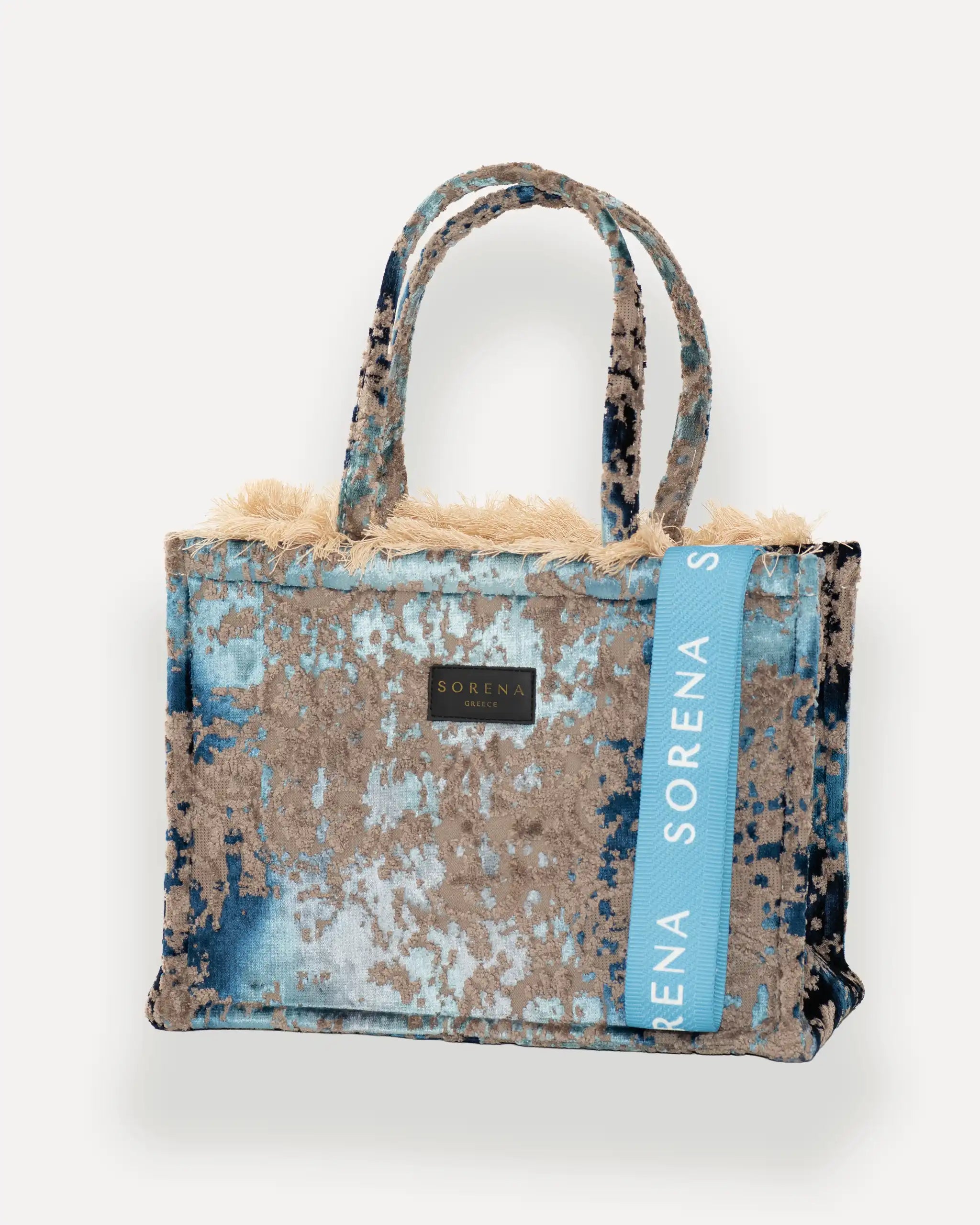 Sorena Greece Medium Tote Bag linksseitig getragen – elegante tote bag mit Fransen und vertikalem „SORENA“-Band, ideal als shopper bag für City-Looks, tote bag beige mit urbanem Charakter.