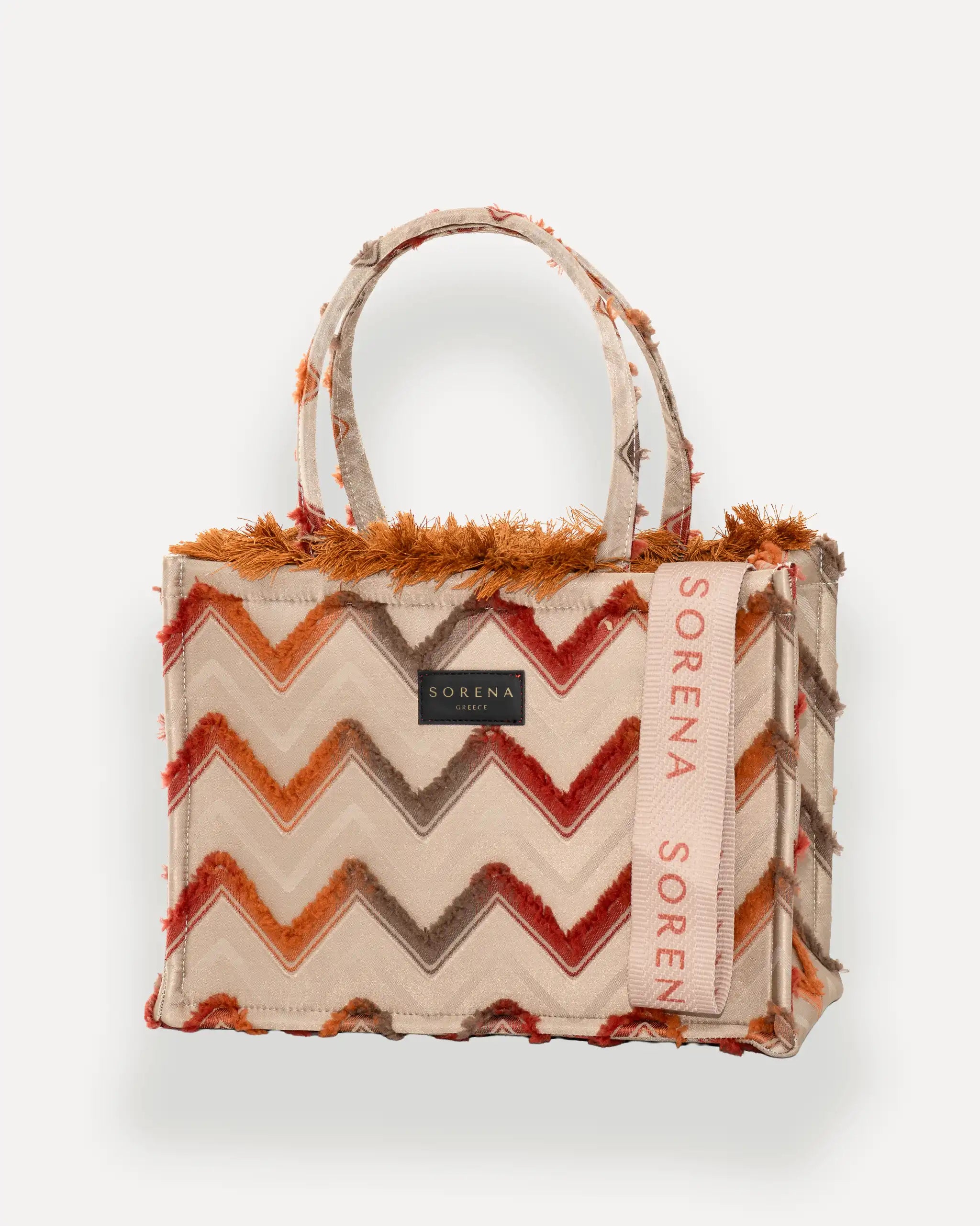 : Sorena Greece Medium Tote Bag linksseitig getragen – shopper beige mit Fransen und rosa „SORENA“-Band, ideale tasche für dinner und city looks, bags schweiz mit Designfokus.