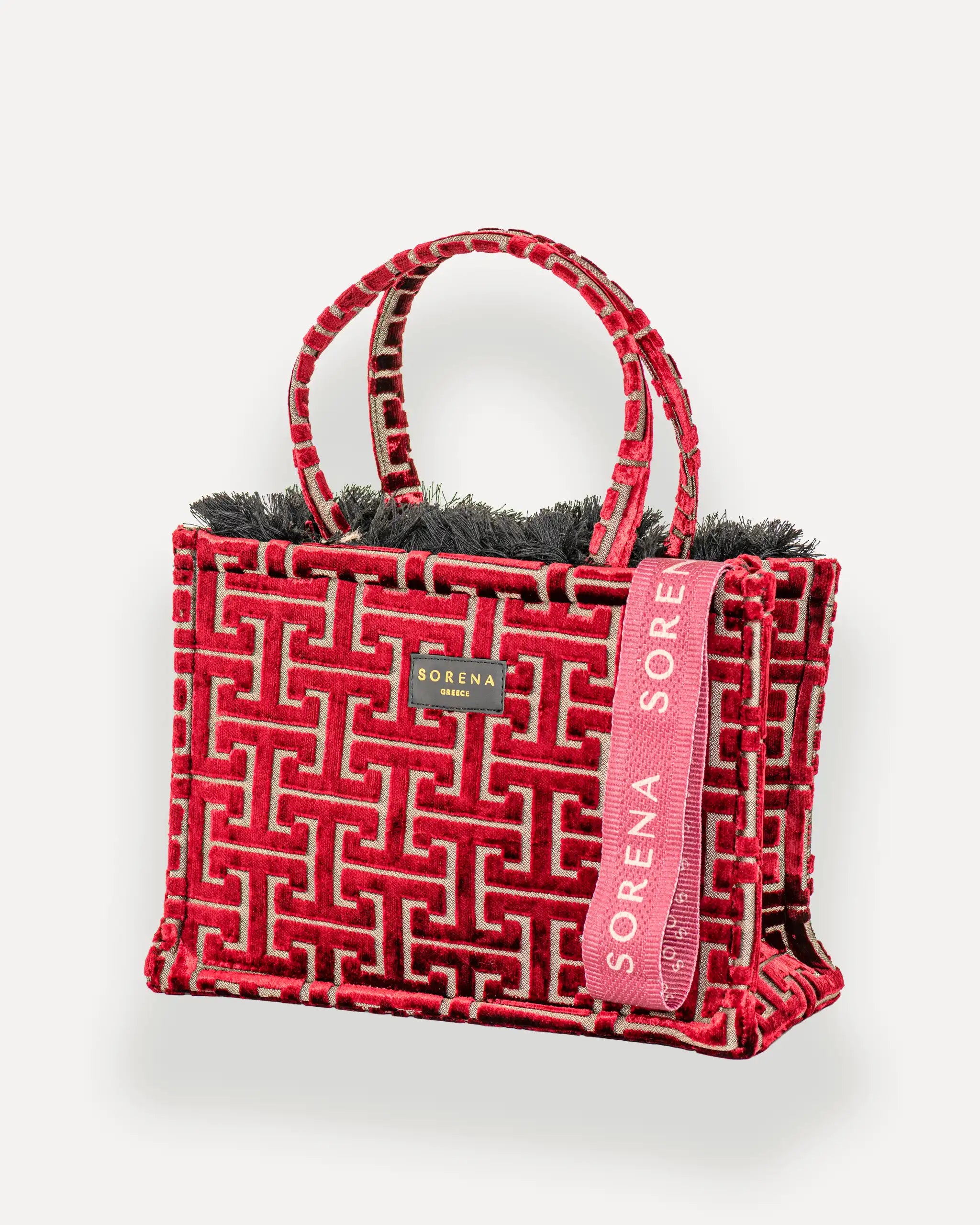 Sorena Greece Medium Tote Bag linksseitig getragen – shopper rot mit Fransen und vertikalem „SORENA“-Band, ideal als tasche für dinner und city looks, bags schweiz mit Designfokus.