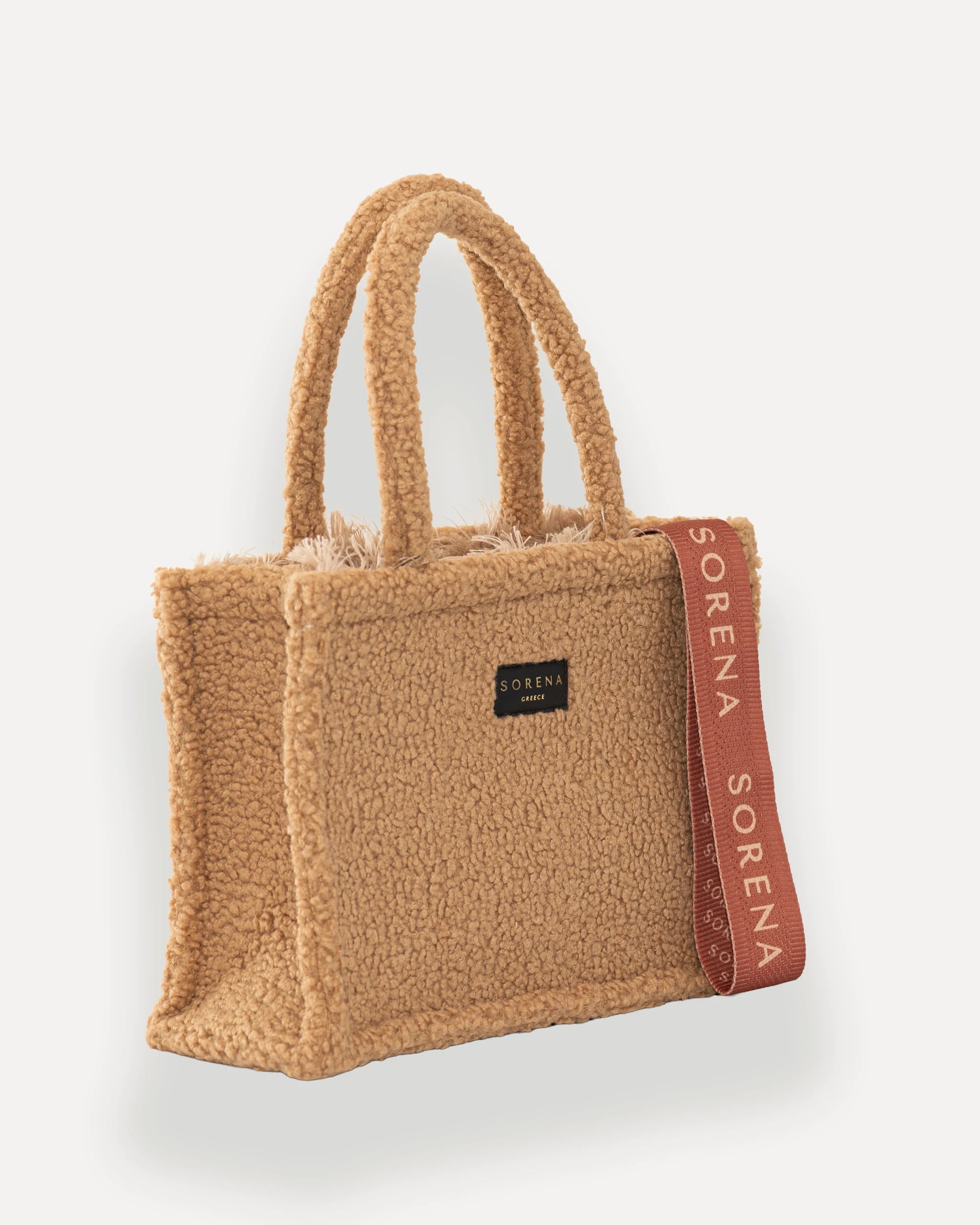 Female Model mit Sorena Greece Tote Bag rechtsseitig getragen – kuschelige teddy tasche mit rosa-braunem Branding, ideale handtasche beige für herbstliche City-Looks, limitierte designer bags schweiz.