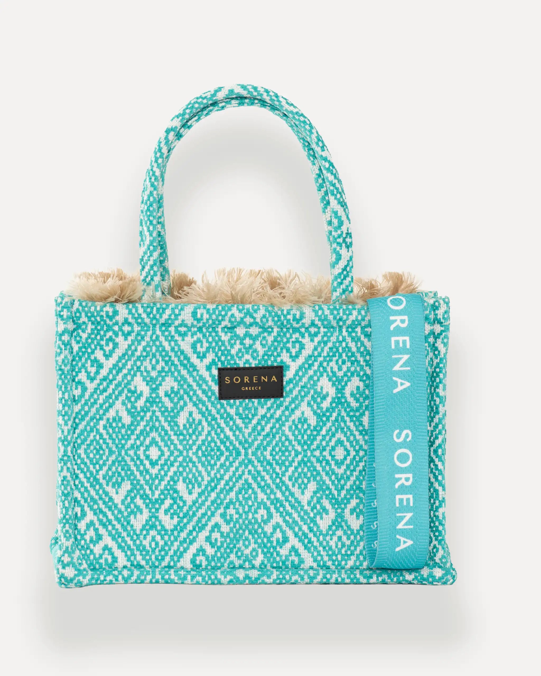 Frontansicht der Sorena Greece Medium Tote Bag – türkis-weißes geometrisches Muster, Fransen, Label und vertikales Branding sichtbar, hochwertige shopper tasche damen schweiz mit Designfokus.