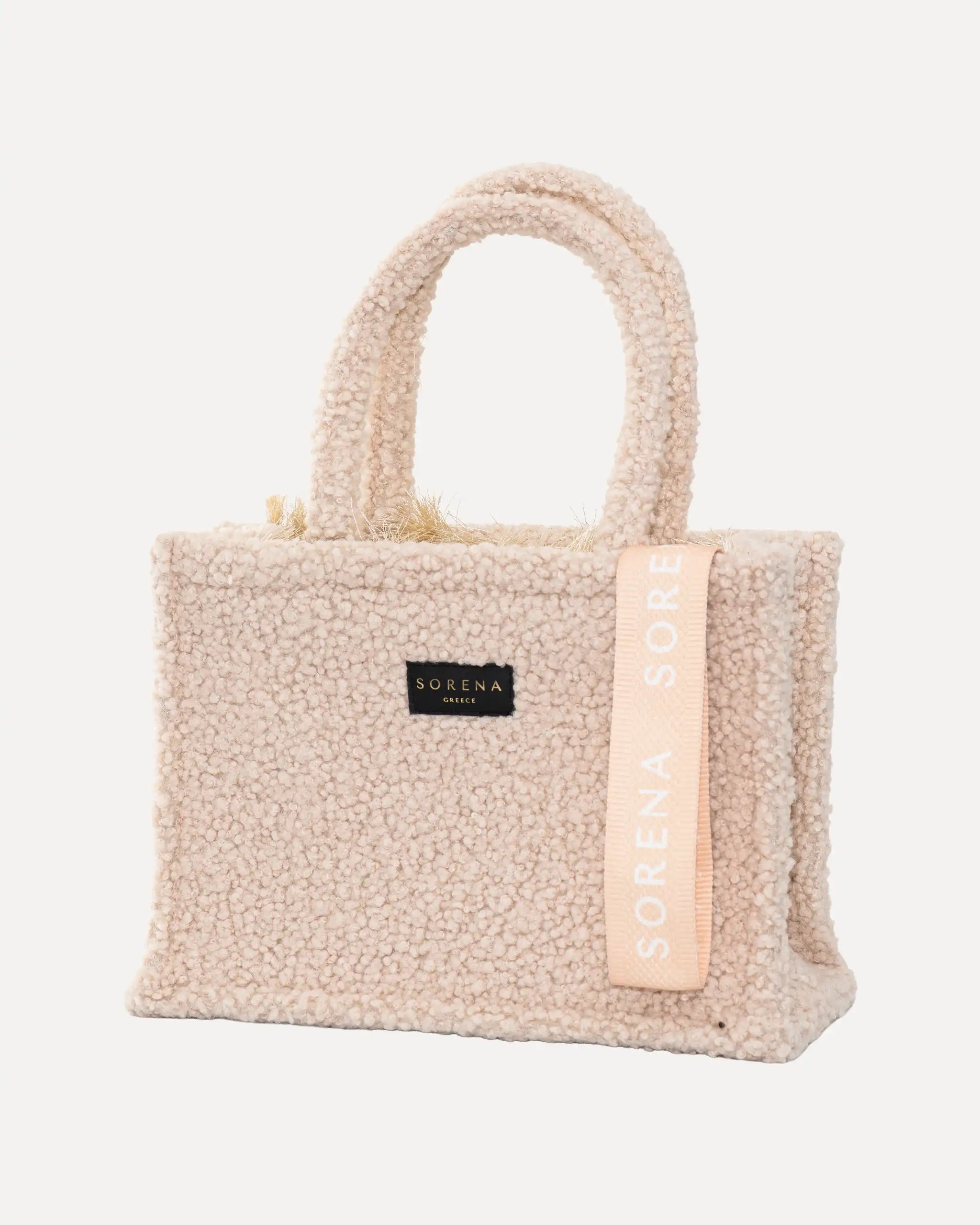 Sorena Greece Medium Tote Bag linksseitig getragen – tote bag beige mit flauschiger Oberfläche und vertikalem „SORENA“-Band, stylische shopper bag für Winter-Outfits, tasche für dinner und city looks