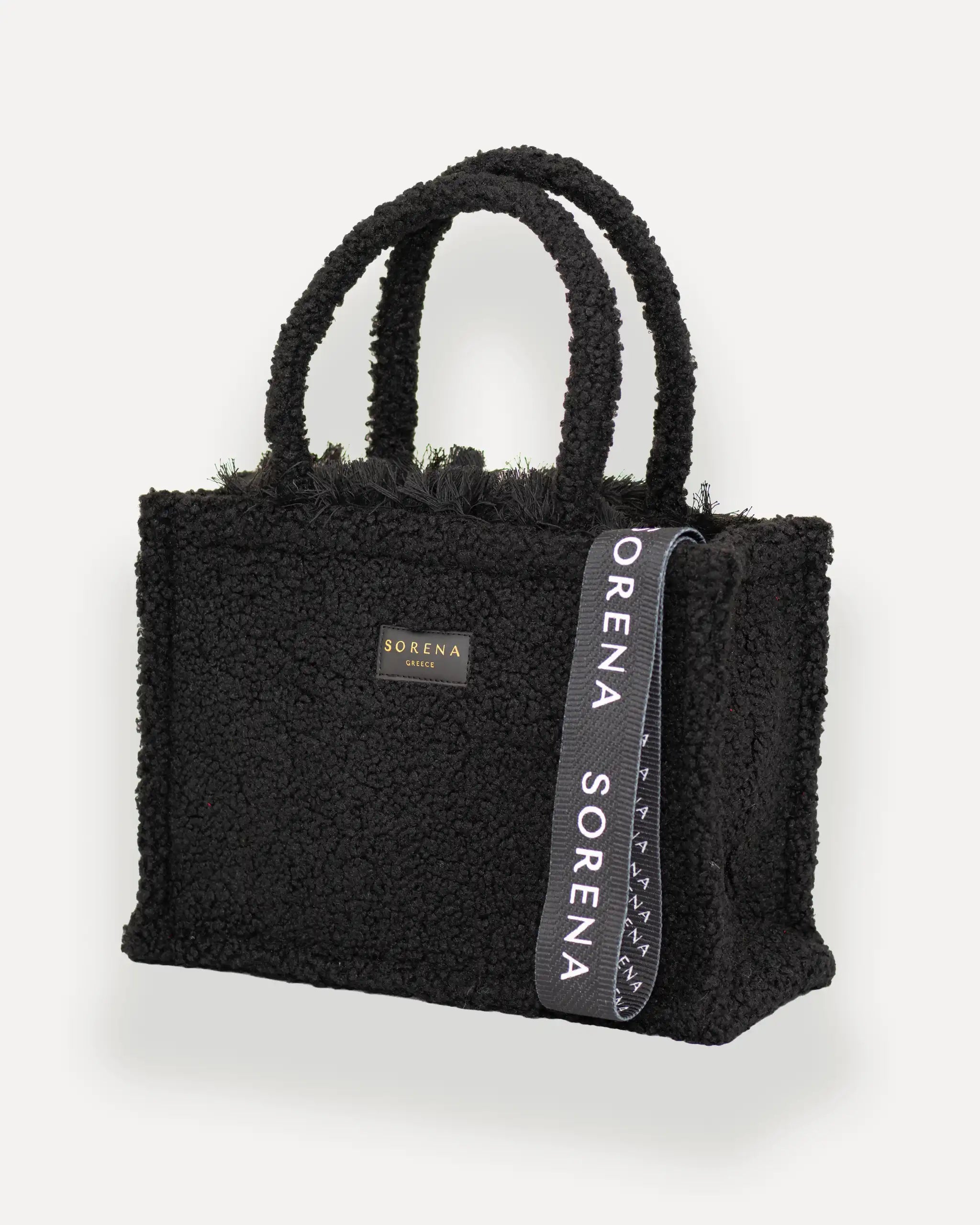 Sorena Greece Medium Tote Bag linksseitig getragen – tote bag schwarz mit flauschiger Textur und vertikalem „SORENA“-Band, stylische shopper bag für Winter-Outfits, tasche für dinner und city looks.