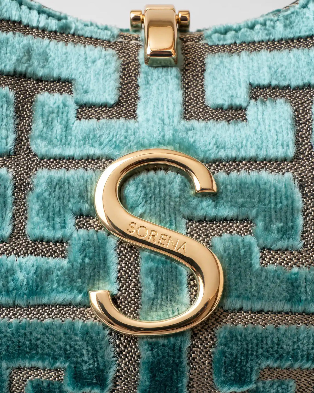 Detailaufnahme des goldenen S Anhängers der Moon Bag Ariadni von Sorena Greece mit sichtbarer Samtstruktur im Mäandermuster, handgefertigt in Griechenland.