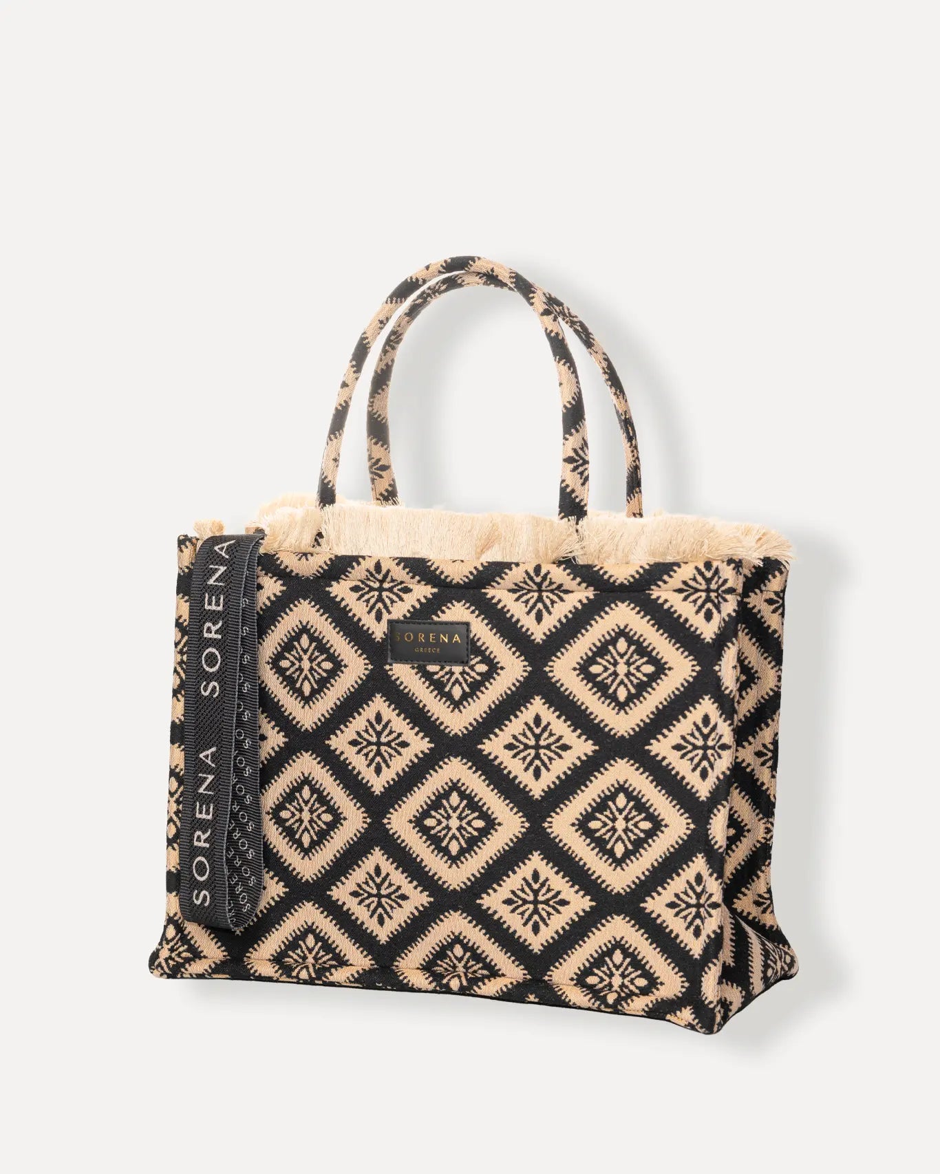 Linke Seite der Cycladitissa Large Tote Bag von Sorena Greece, schwarzes Jacquard Gewebe mit hellem Beige Muster, fester Boden, breite Tragegriffe.