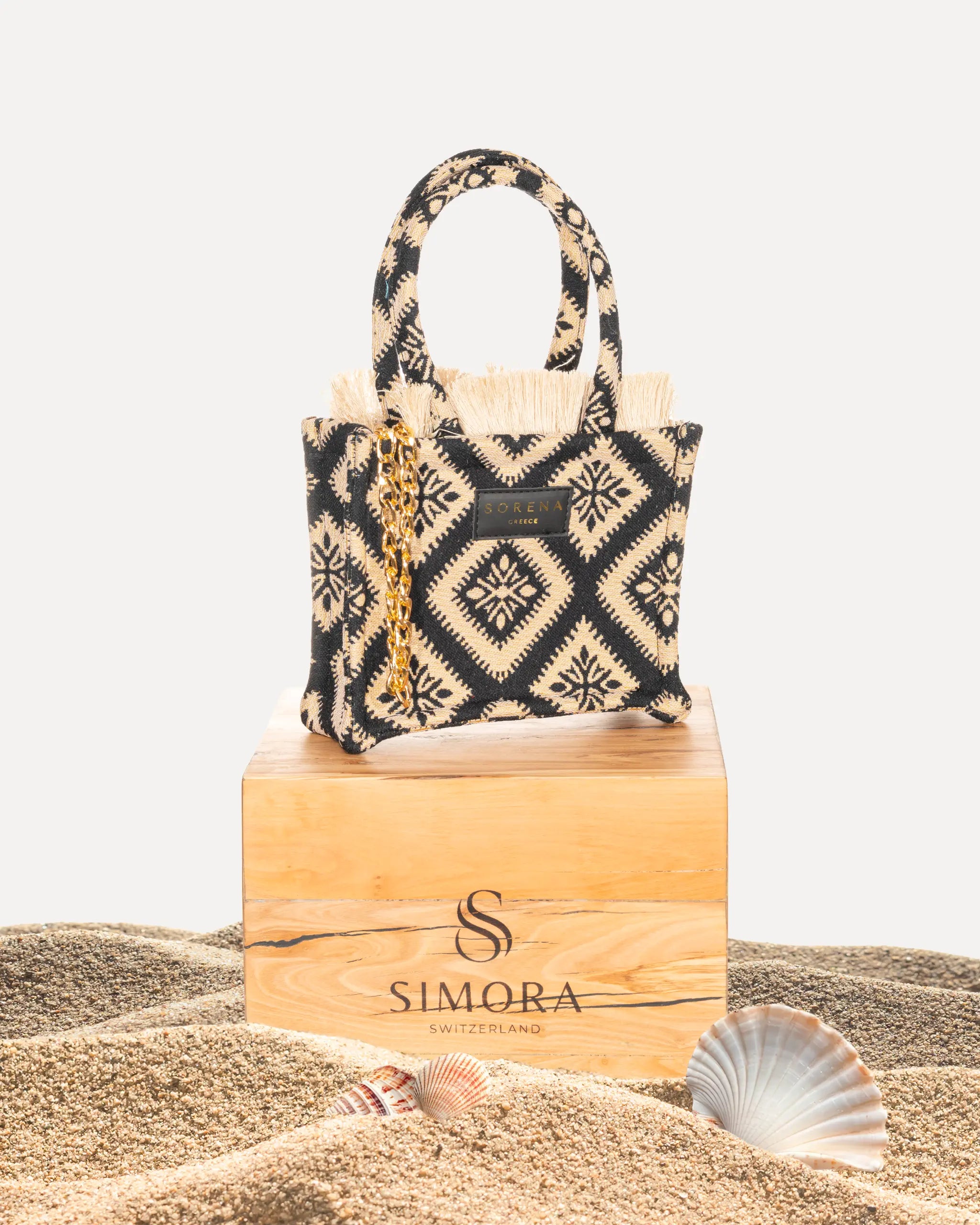 Sorena Greece Cycladitissa Mini Tote Bag auf SIMORA Olivenholzsockel Frontansicht, Jacquard Schwarz Beige Stern Muster, kleine handgefertigte Tasche Griechenland Produktfoto