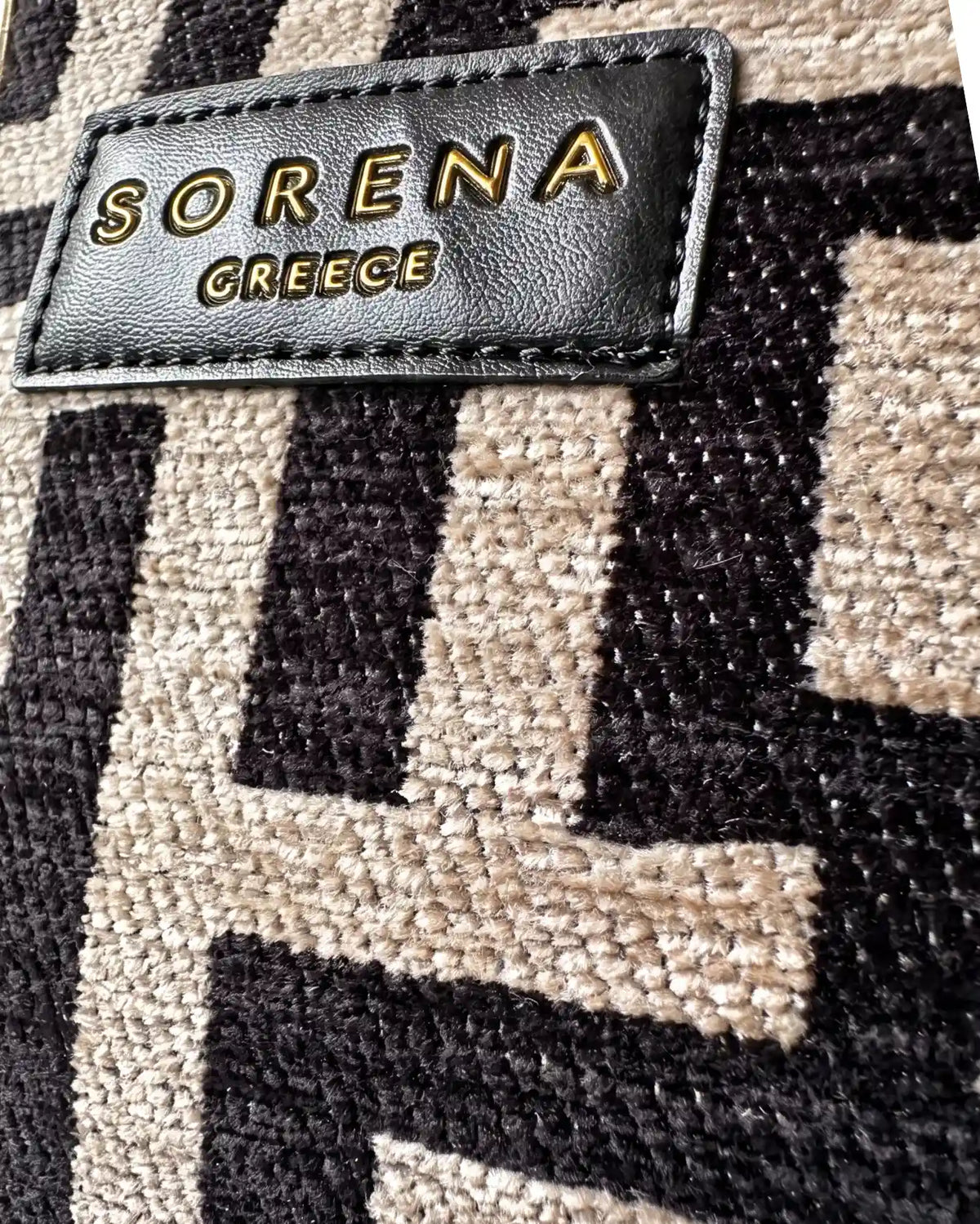 Nahaufnahme der Galleria Domna Large von Sorena Greece mit Fokus auf die Webstruktur des Mäandermusters in Beige und Schwarz und das schwarze Leder Label mit goldener Prägung SORENA GREECE, handgefertigtes Detail aus Griechenland