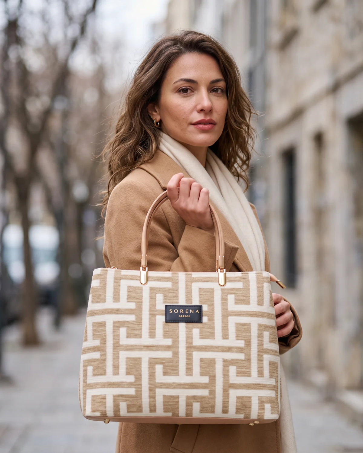 Model trägt die Galleria Melina Large von Sorena Greece zu winterlichem Look mit Camel Mantel, eine handgefertigte Handtasche aus Griechenland, erhältlich bei SIMORA in der Schweiz.