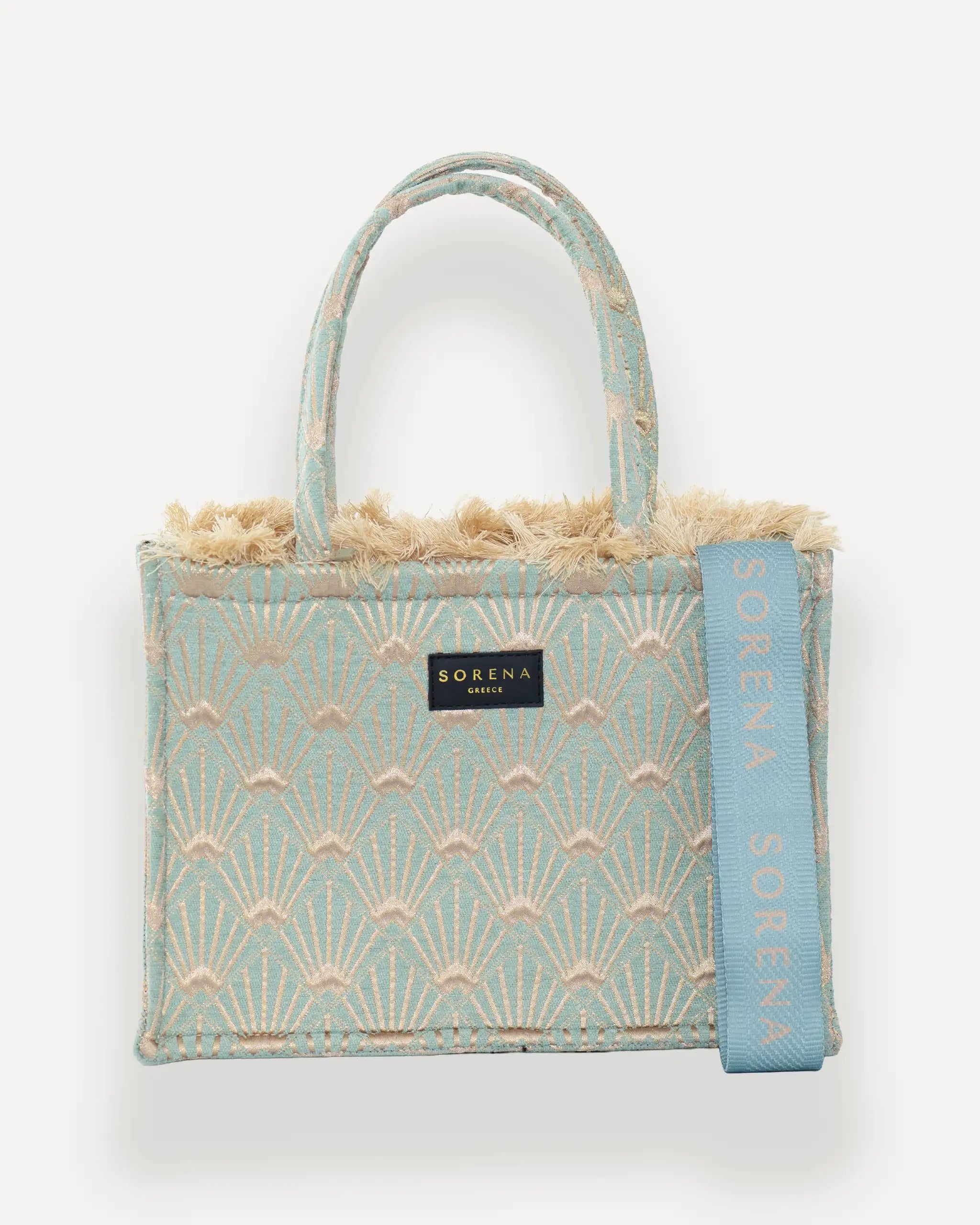Frontansicht der Sorena Greece Medium Tote Bag – hellblau-beiges Fächer-Muster, Fransen, Label und vertikales Branding sichtbar, hochwertige shopper tasche damen schweiz mit Designfokus.