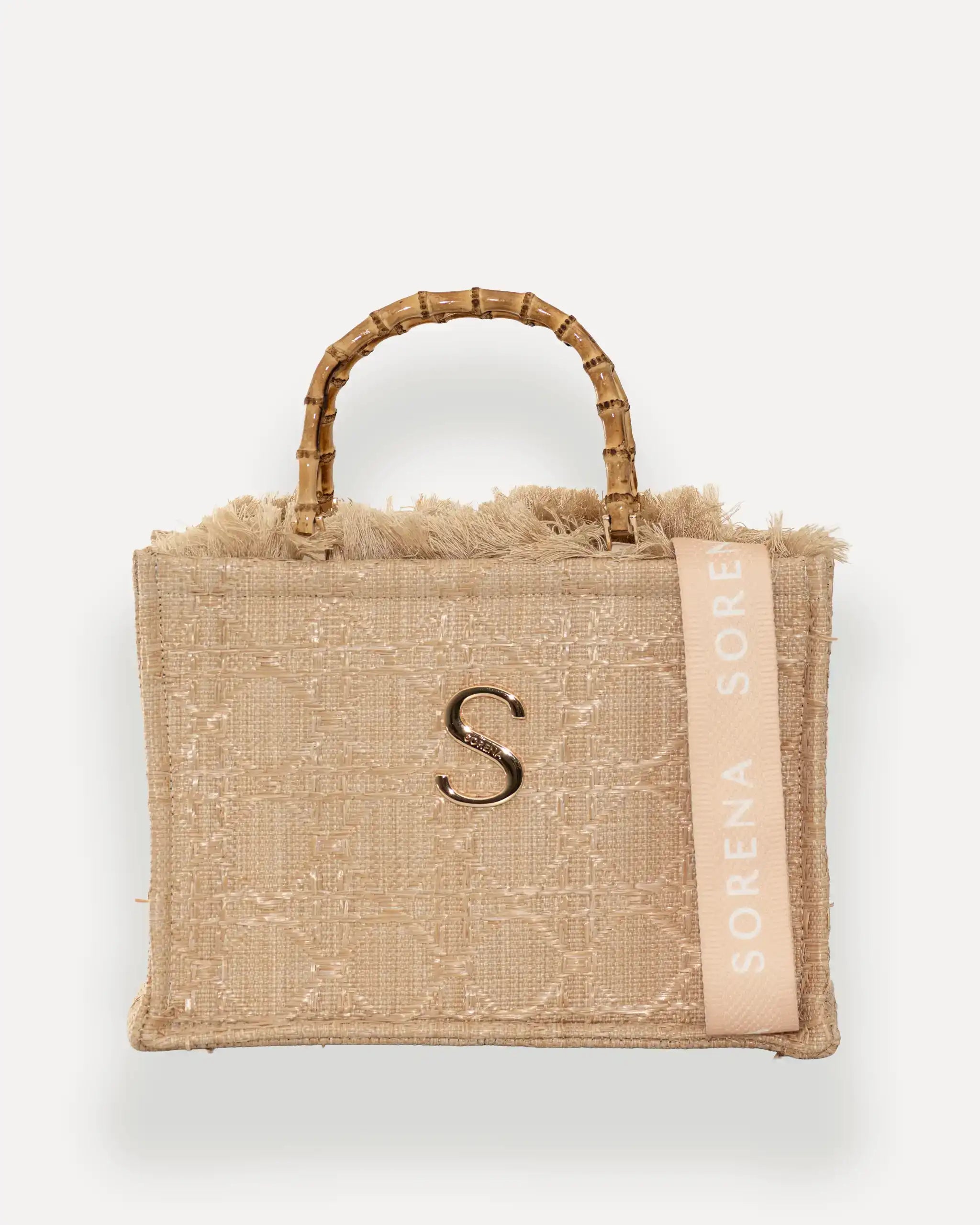 Frontansicht der Sorena Greece Medium Tote Bag – gewebte Oberfläche in Beige, Fransen, metallisches „S“-Emblem und vertikales Branding sichtbar, hochwertige shopper tasche damen schweiz mit Designfokus.