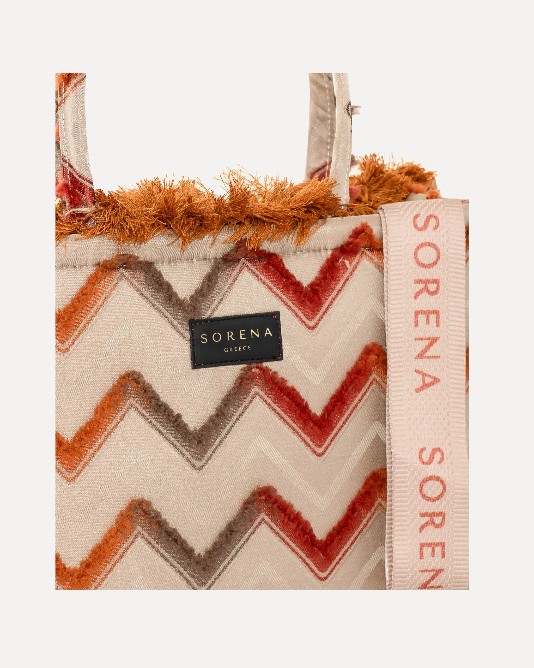 Detailansicht der Sorena Greece Tote Bag – strukturierte Oberfläche mit geometrischem Webmuster in Rot und Orange, Label „SORENA GREECE“, vertikales Band mit Branding, perfekte tote bag für Business & Freizeit, handtaschen damen mit Statement.