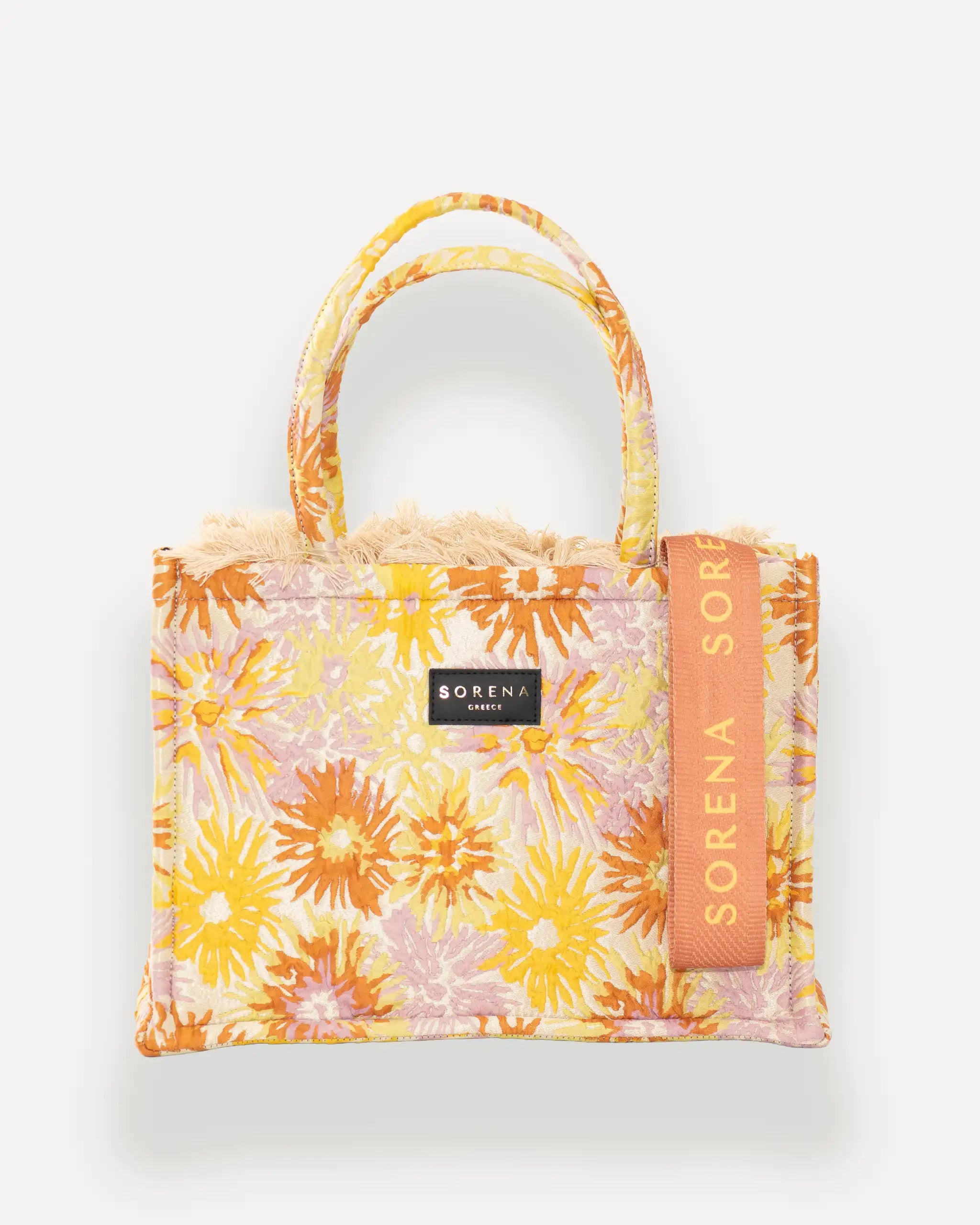 Frontansicht der Sorena Greece Medium Tote Bag – florales Muster in Orange, Gelb und Flieder, Fransen, Label und vertikales Branding sichtbar, hochwertige shopper tasche damen schweiz mit Designfokus.