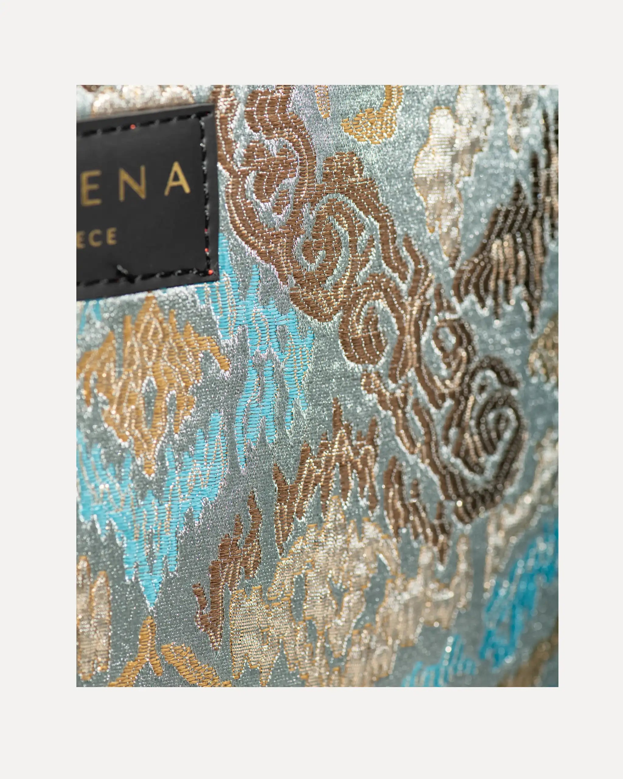 Detailansicht der Sorena Greece Tote Bag – strukturierte Oberfläche mit federartiger Textur in Beige und Braun, Label „SORENA GREECE“, vertikales Band mit Branding, perfekte tote bag mit Federoptik für Business & Freizeit, handtaschen damen mit Statement.