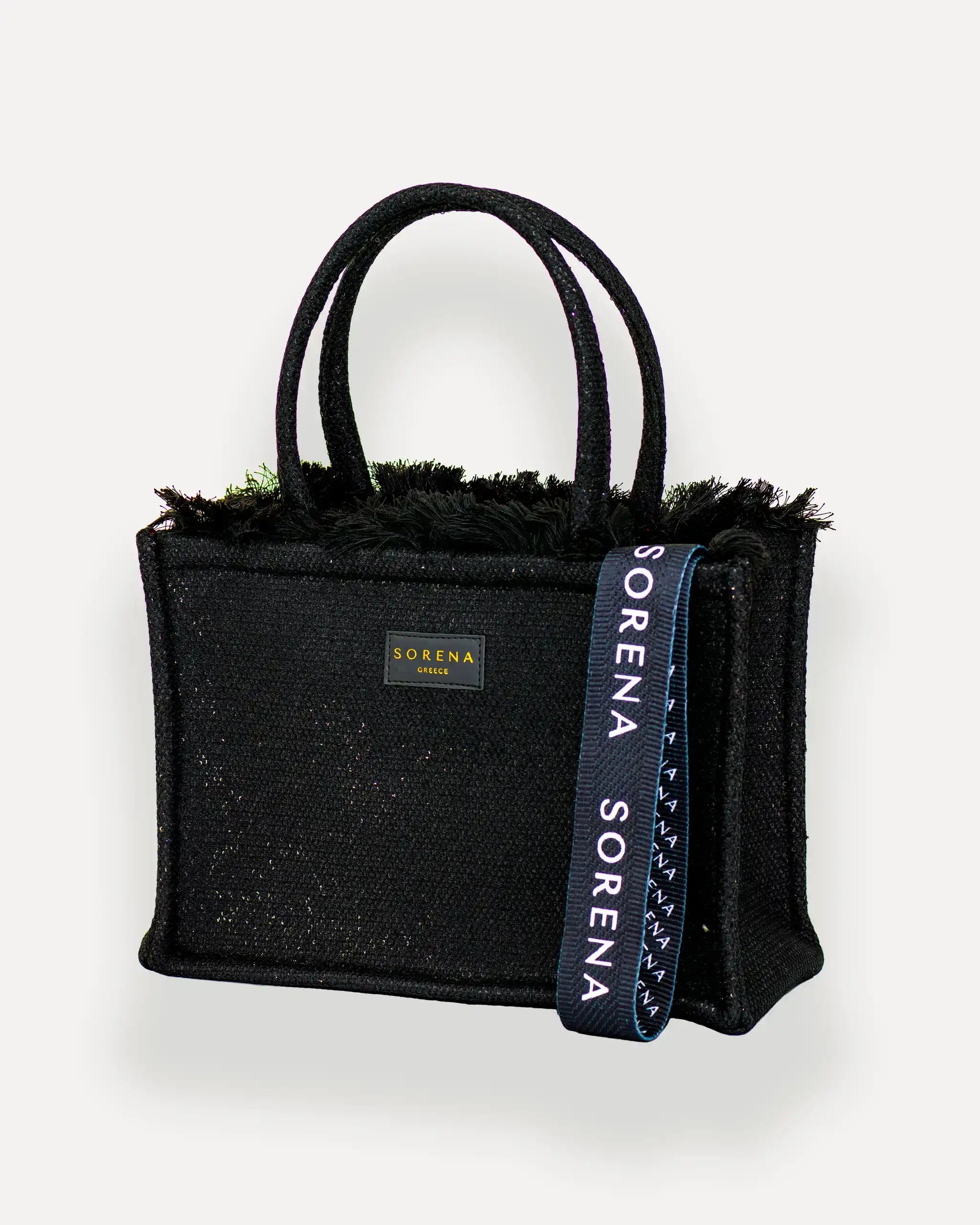 Sorena Greece Medium Tote Bag linksseitig getragen – tote bag schwarz mit Fransen und vertikalem „SORENA“-Band, ideal als shopper bag für City-Looks, tasche für dinner und city looks.