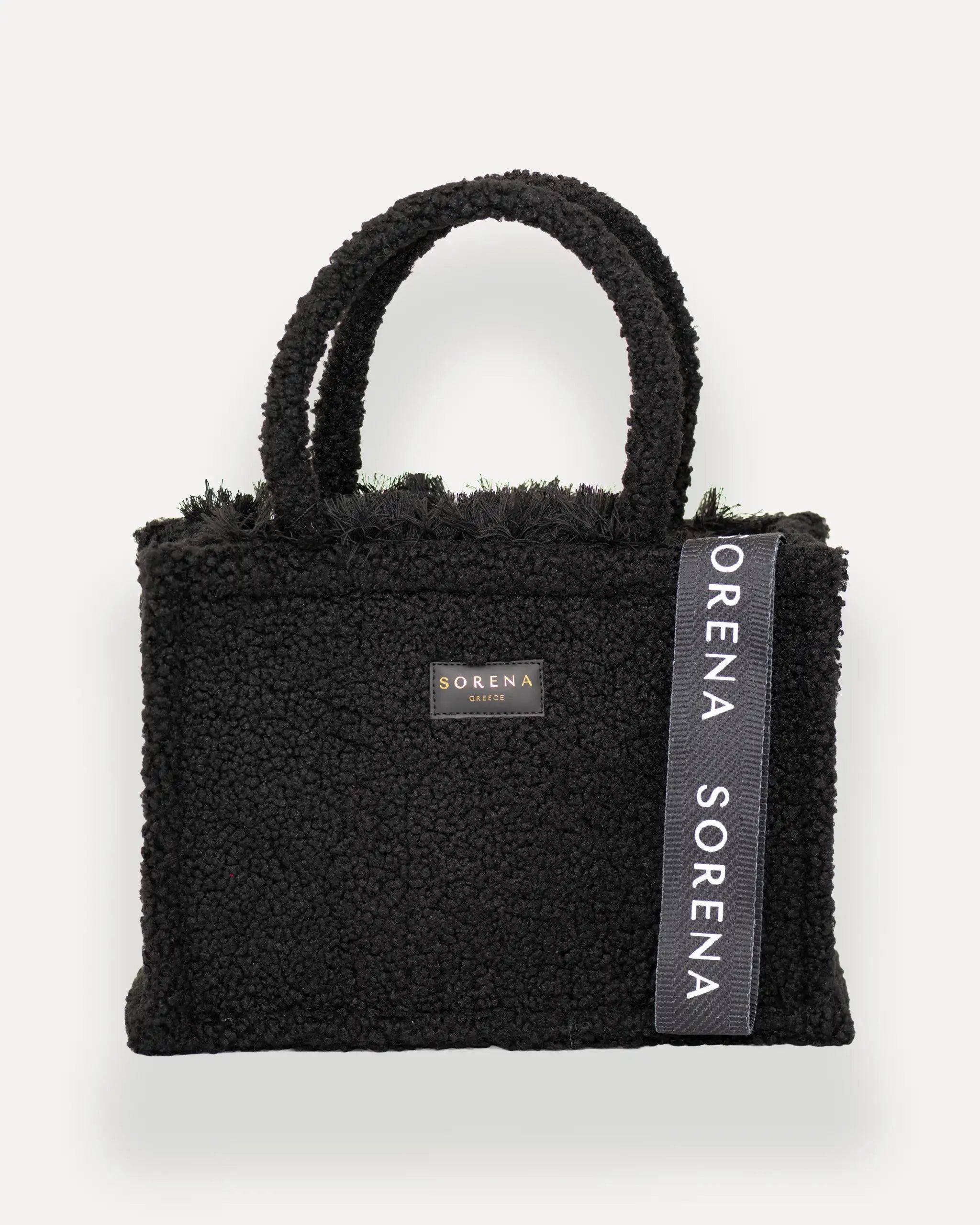 Frontansicht der Sorena Greece Medium Tote Bag – schwarze teddy-Oberfläche mit Label und vertikalem Branding, hochwertige shopper tasche damen schweiz für Winter-Looks.