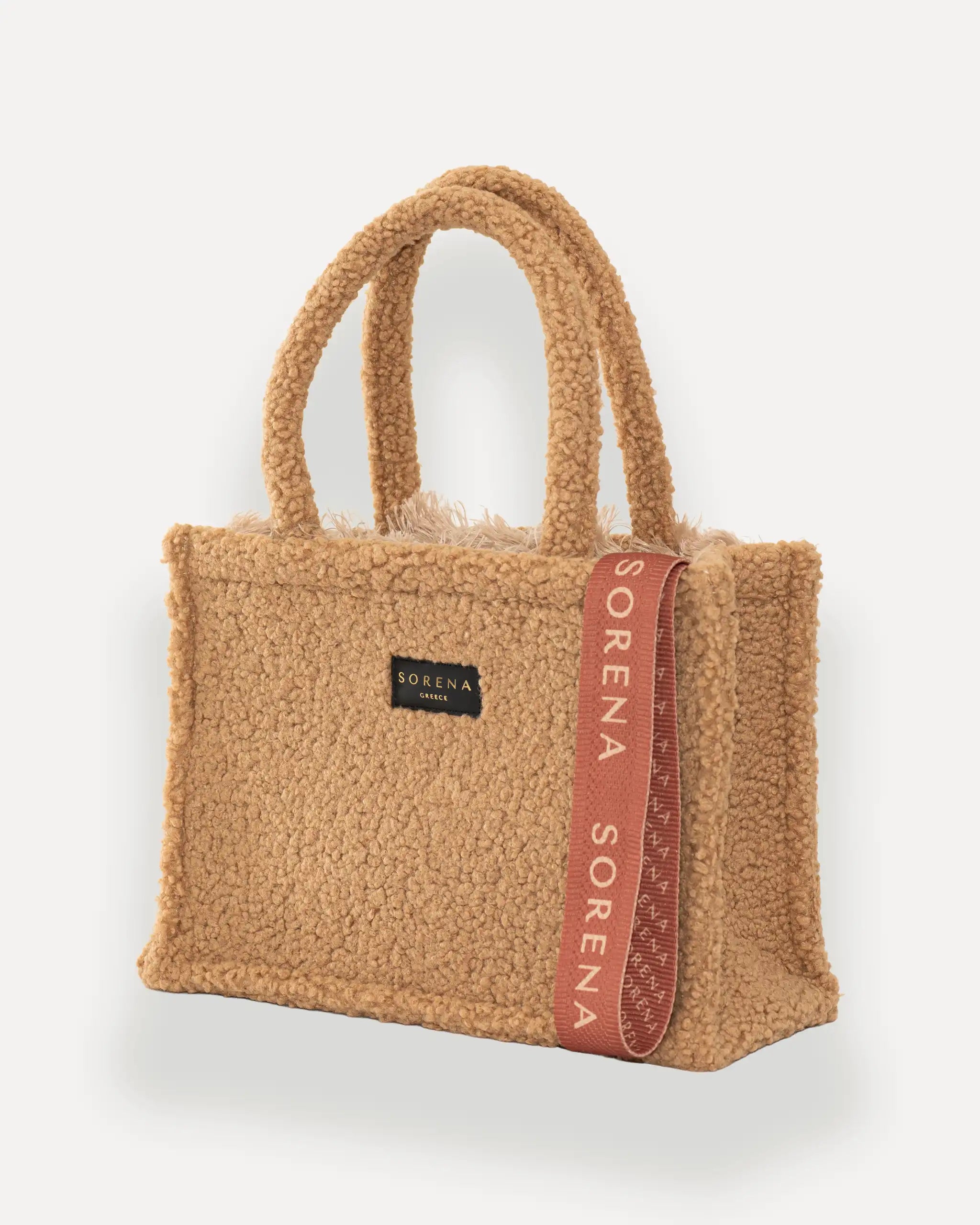 Sorena Greece Medium Tote Bag linksseitig getragen – tote bag beige mit flauschiger Oberfläche und vertikalem „SORENA“-Band, stylische shopper bag für Winter-Outfits, tasche für dinner und city looks.