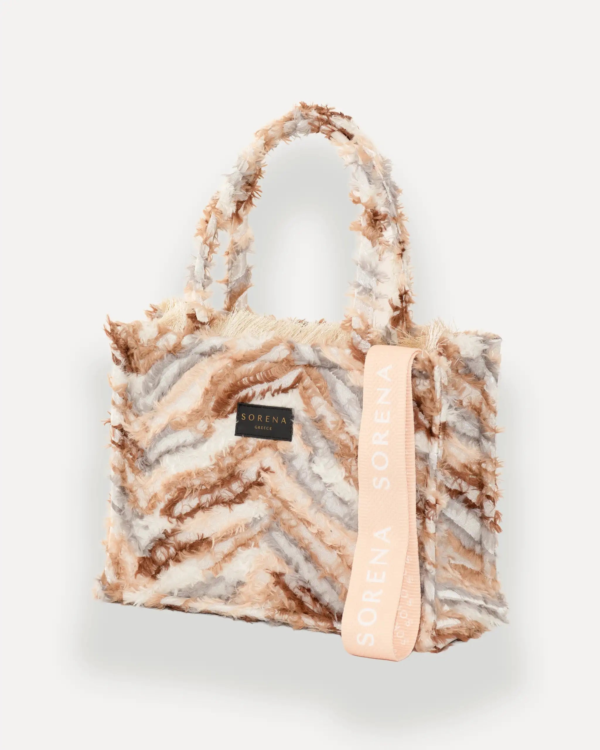 Sorena Greece Medium Tote Bag linksseitig getragen – shopper beige mit federartigem Muster, Fransen und rosa „SORENA“-Band, ideale tasche für dinner und city looks, bags schweiz mit Designfokus.
