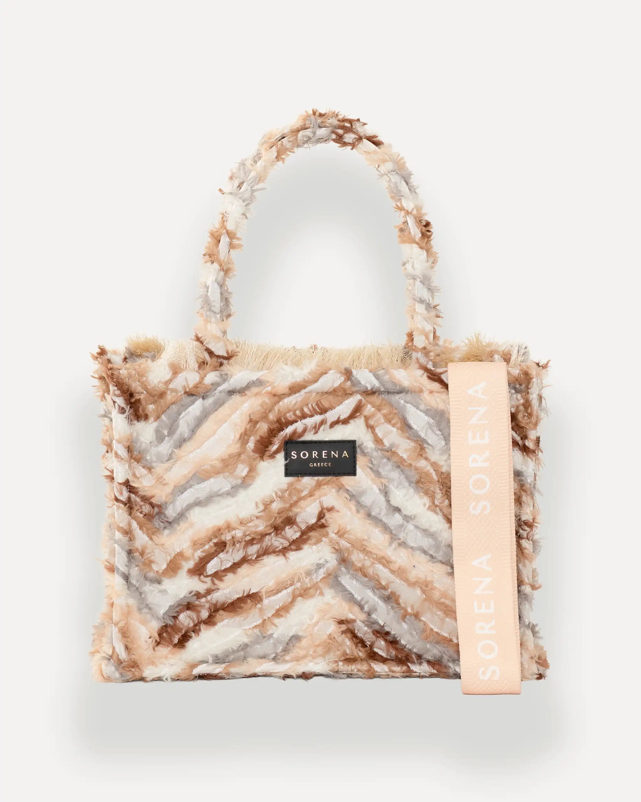  Frontansicht der Sorena Greece Medium Tote Bag – federartige Chevron-Struktur in warmen Tönen, Fransen, Label und vertikales Branding sichtbar, hochwertige shopper tasche damen schweiz mit Designfokus.