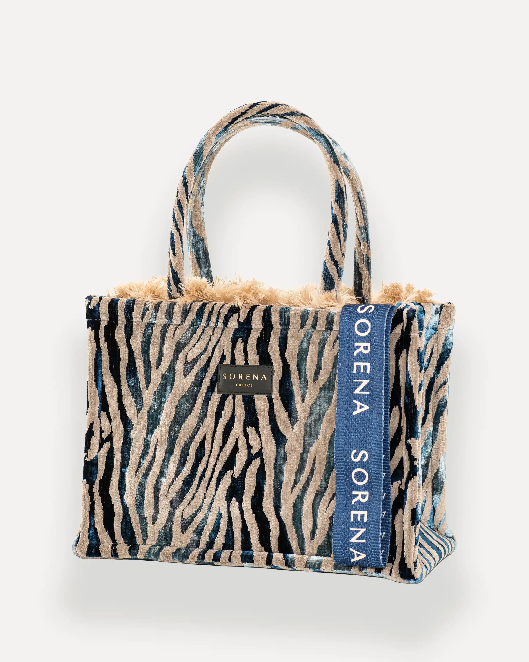 Sorena Greece Medium Tote Bag linksseitig getragen – elegante tote bag mit Fellrand und vertikalem „SORENA“-Band, ideal als shopper bag für City-Looks, taschen damen mit Charakter.