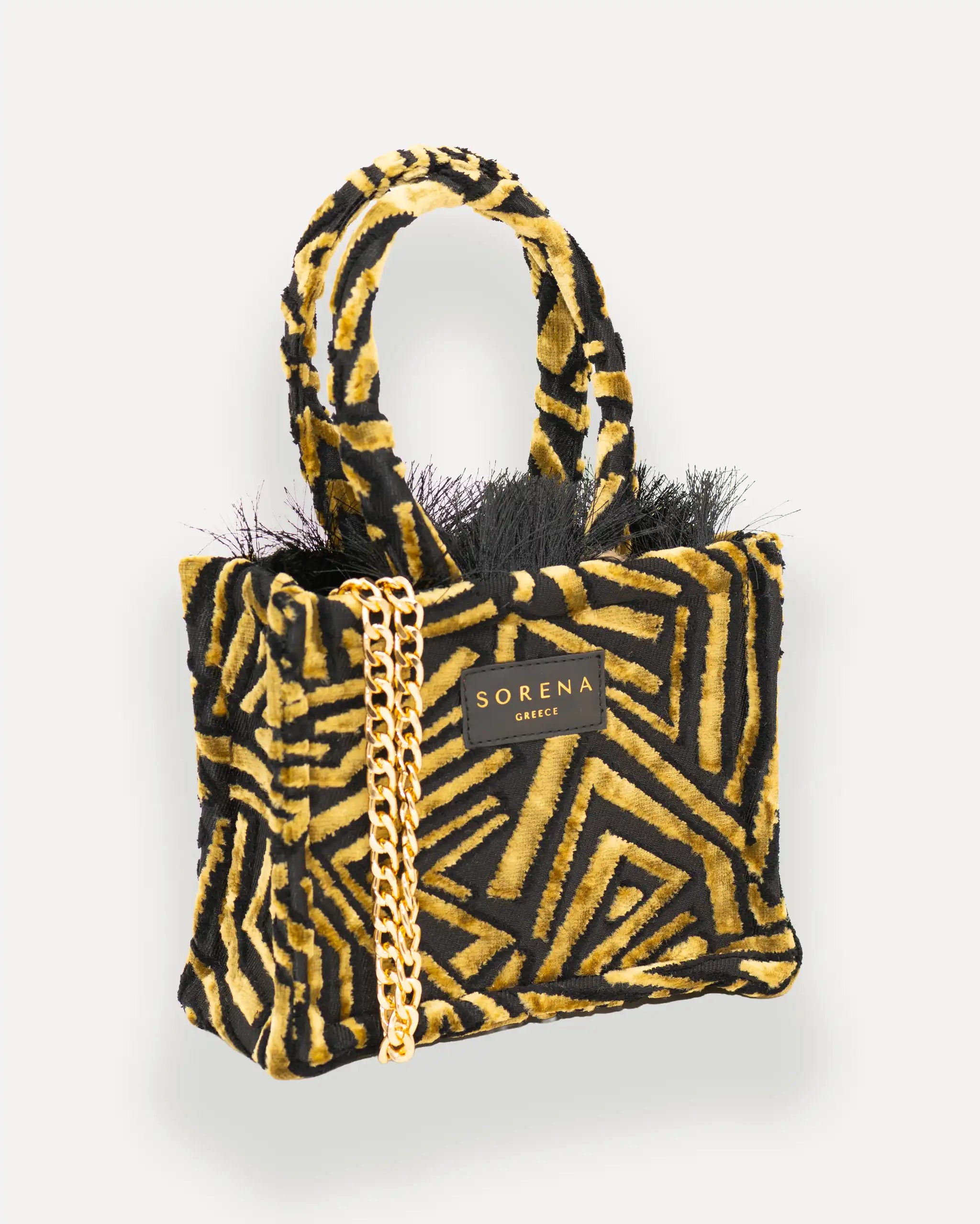 Female Model mit Sorena Greece Mini Bag rechtsseitig getragen – elegante umhängetasche damen mit geometrischem Muster, crossbody tasche mit goldener Kette, bags schweiz mit Statement-Charakter.