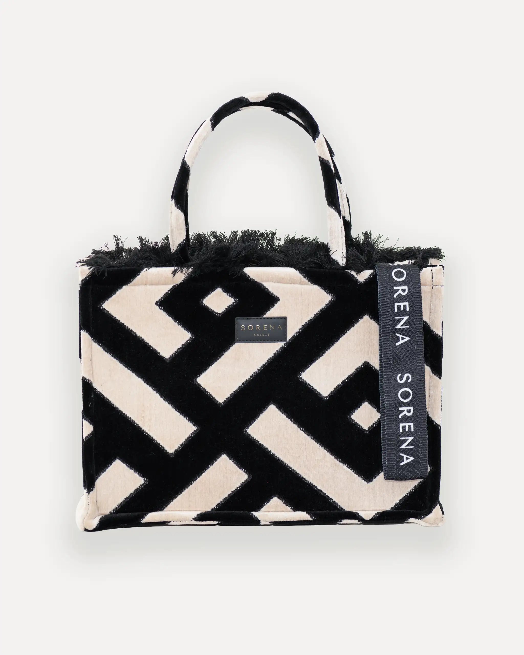 Frontansicht der Sorena Greece Large Tote Bag – geometrisches Muster in Schwarz und Beige, Fransen, Label und vertikales Branding sichtbar, hochwertige shopper tasche damen schweiz mit Designfokus.